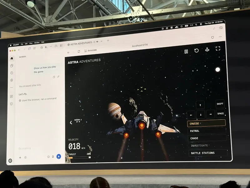 A large screen in an industrial event space shows a space-flight game called “AS